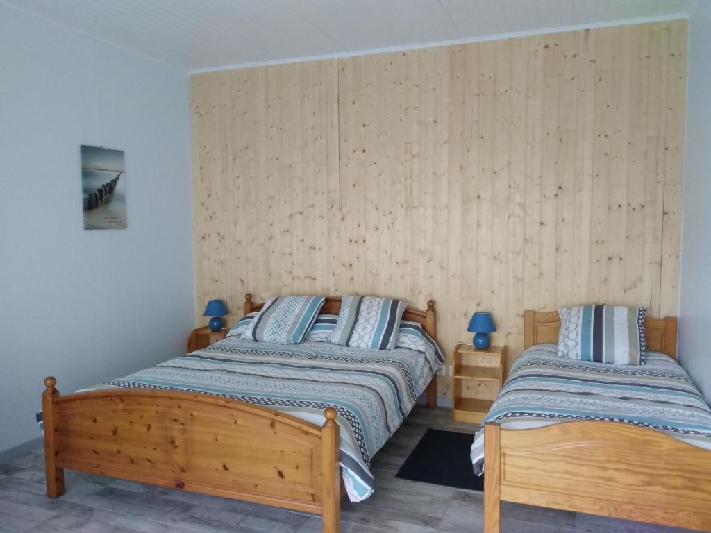 two twin beds in a bedroom with wooden walls at La Forge in Sore