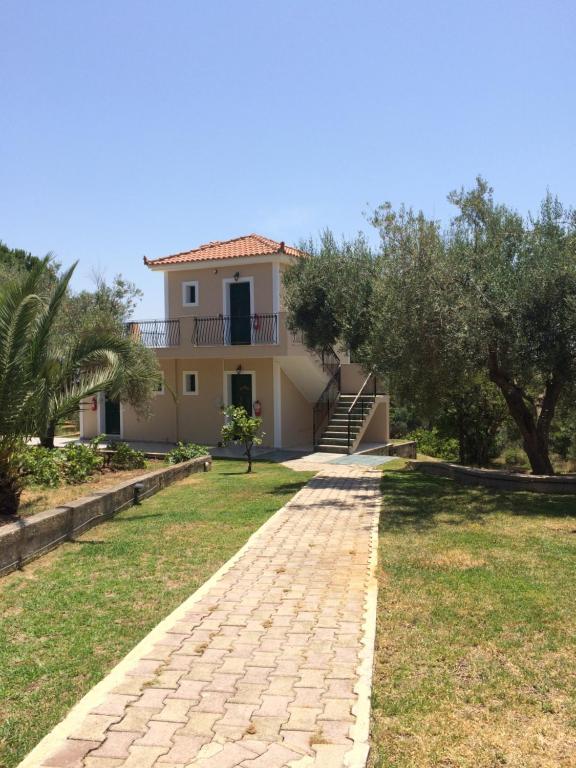 a villa with a pathway in front of a house at Koukounaries Studios in Skala