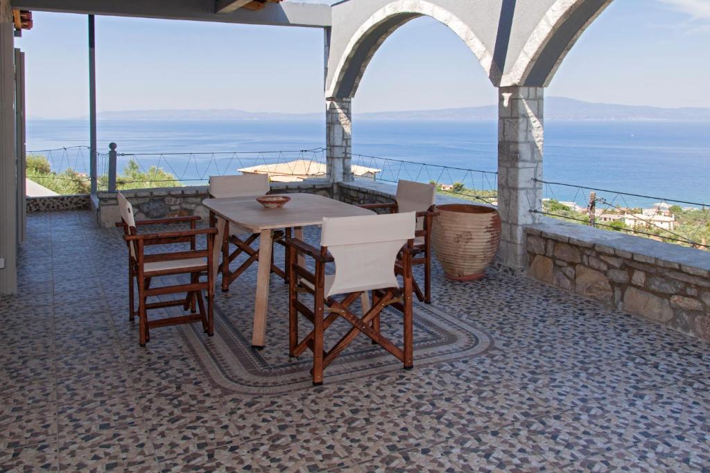 einen Tisch und Stühle auf einem Balkon mit Meerblick in der Unterkunft Ellinas Homes in Megáli Mandínia