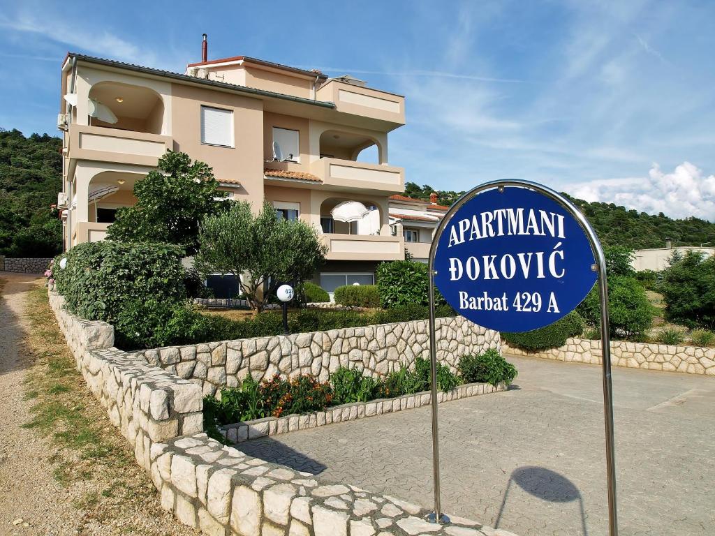 um sinal para um hotel em frente a um edifício em Apartments Đoković em Rab