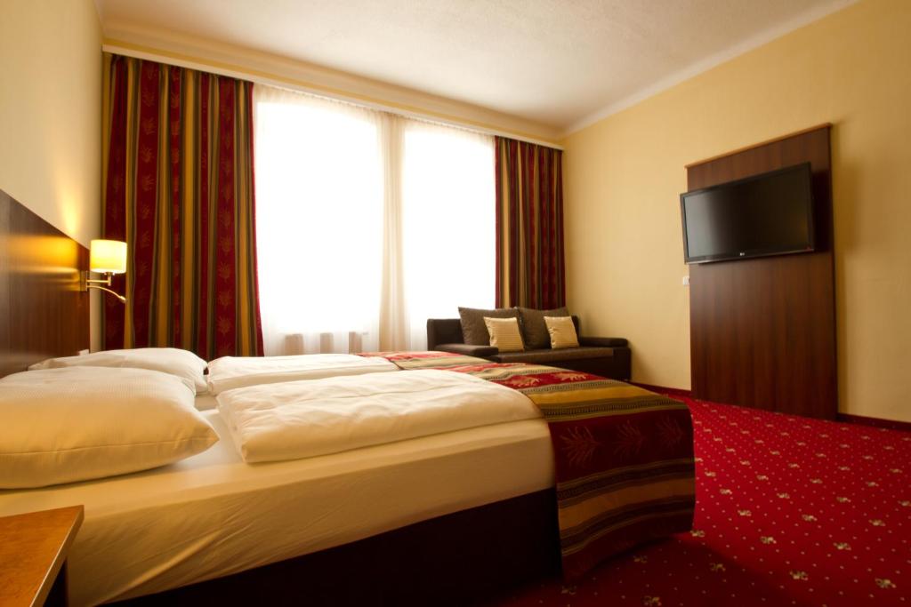 um quarto de hotel com uma cama grande e uma televisão em Residenz Royal em Gmünd