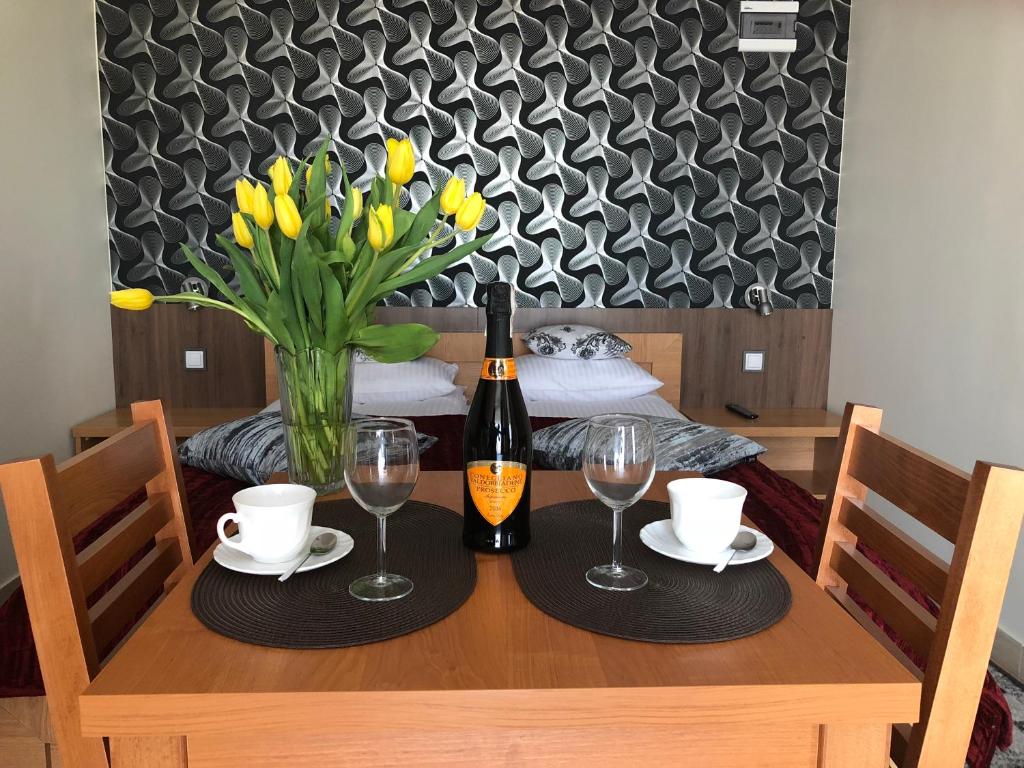 una mesa con una botella de vino y un jarrón de flores en Comfort-24 Plus, en Słupca