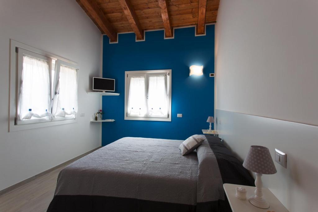 una camera blu con un letto e due finestre di Il Rifugio Del Tempo a Roccasecca