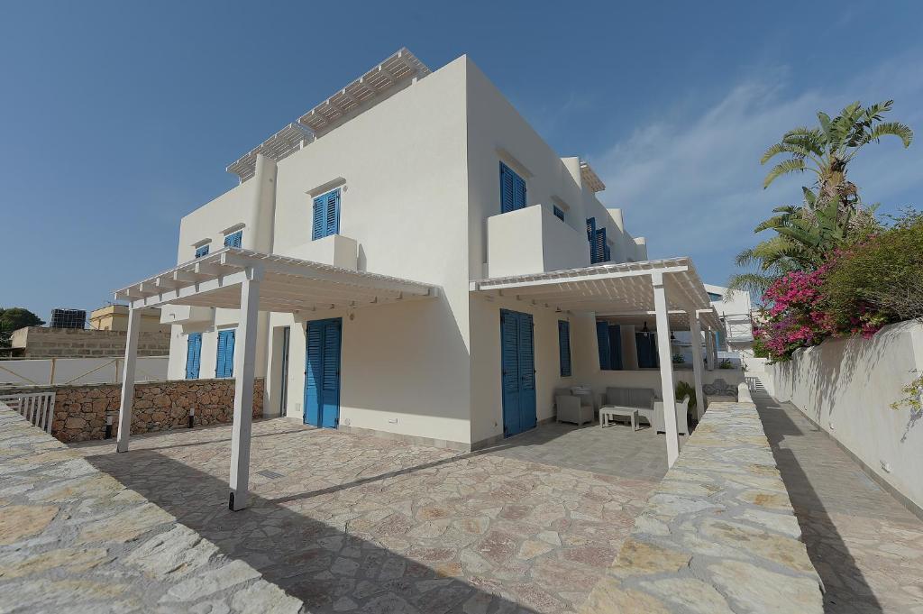 a white house with a patio in front of it at Isule Apartments in San Vito lo Capo