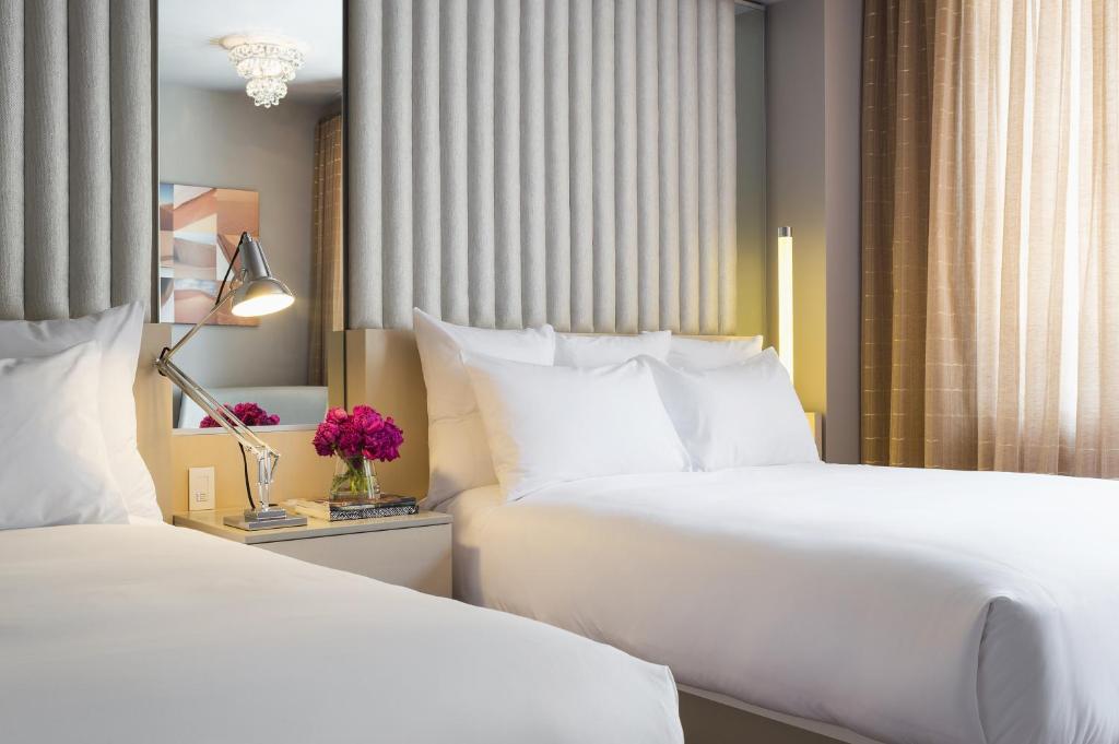 2 camas en una habitación de hotel con almohadas blancas en 21c Museum Hotel Durham, en Durham