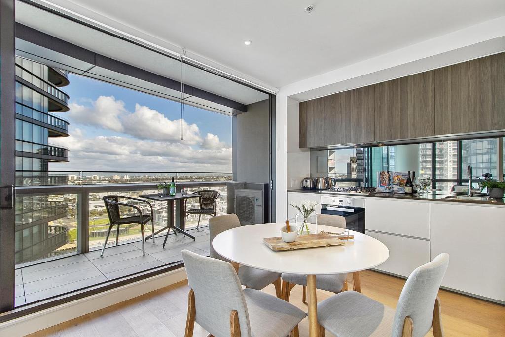 cocina con mesa y sillas y ventana grande en Stylish Waterfront Apartment With Docklands Views, en Melbourne
