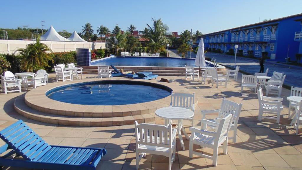 un grupo de sillas y mesas y una piscina en Apartamento Praia Taperapuan, en Porto Seguro