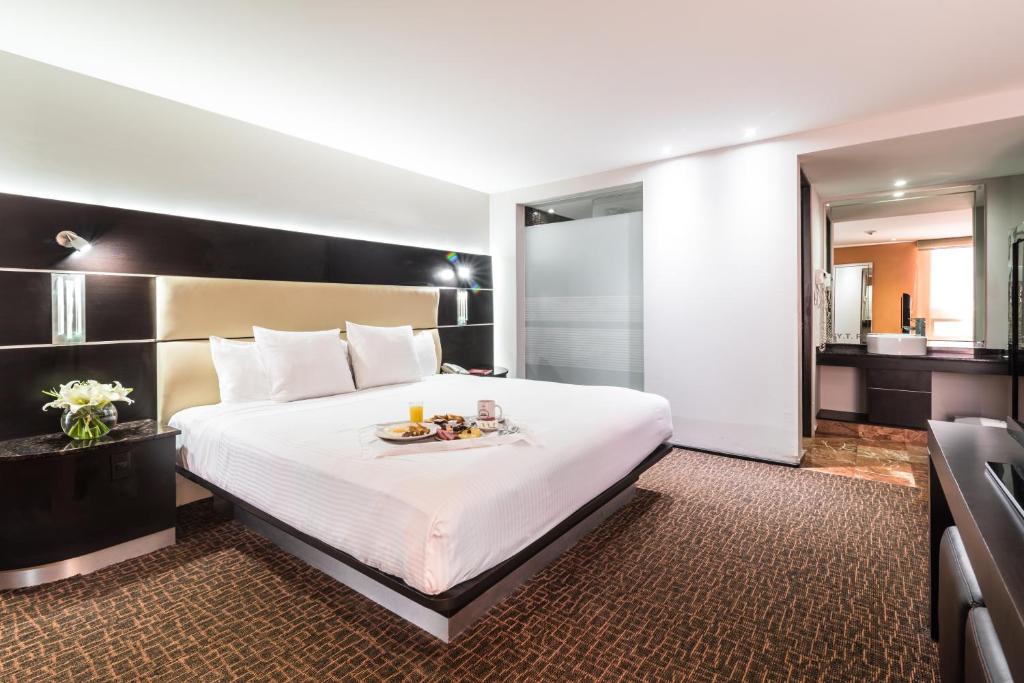a hotel room with a bed with a tray of food on it at Exe Cities Reforma in Mexico City