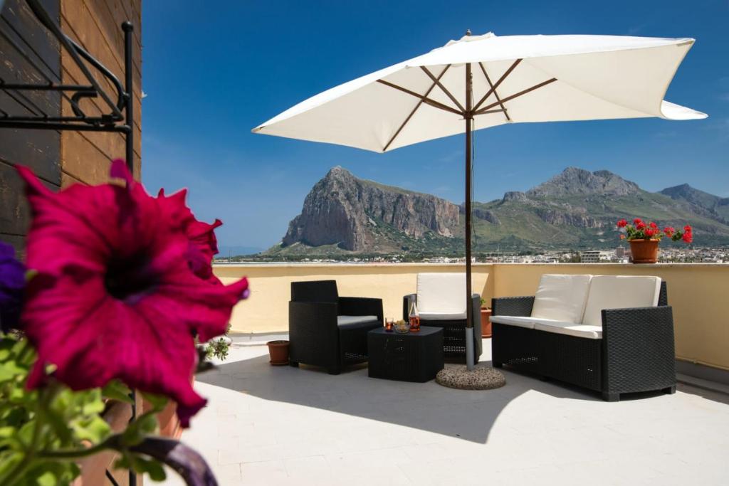 eine Terrasse mit Stühlen, Sonnenschirm und Strand in der Unterkunft Il Torrazzo da Francesca in San Vito lo Capo