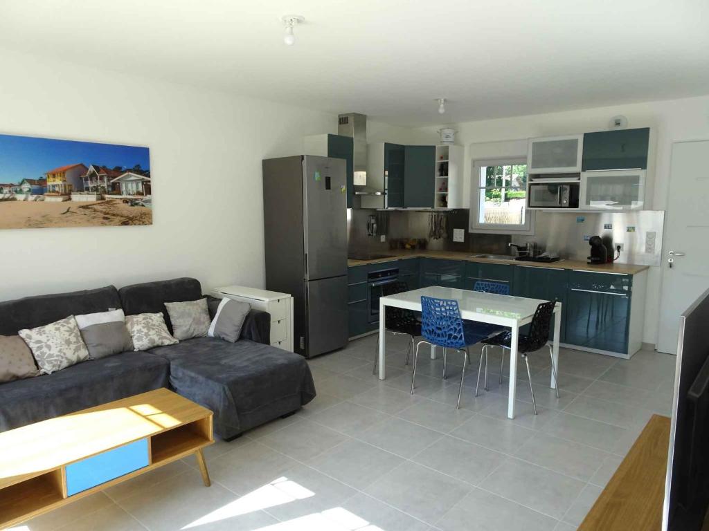 a living room with a couch and a kitchen at Villa du Cabestan in Andernos-les-Bains