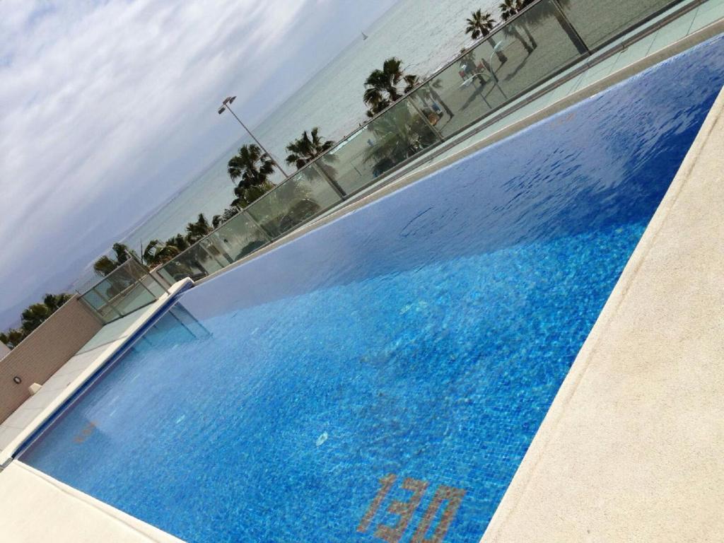 ロケタス・デ・マルにあるPiso 1a Linea piscina 3Dのヤシの木と海の広い青いスイミングプール