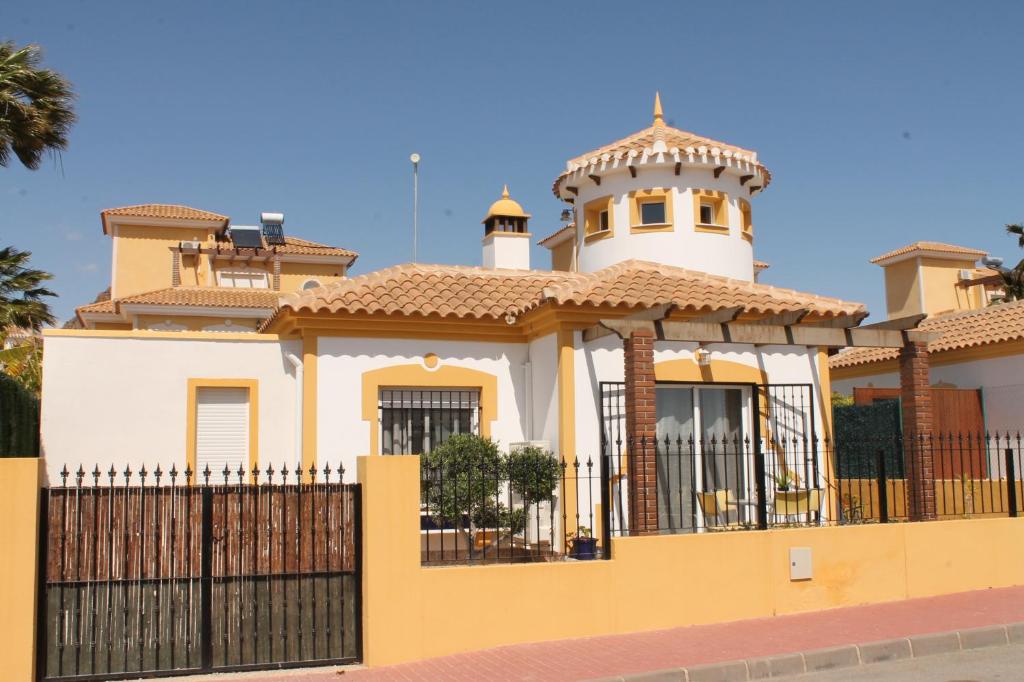 una casa amarilla y blanca con una valla negra en Casa Alegria Mazarron, en Mazarrón