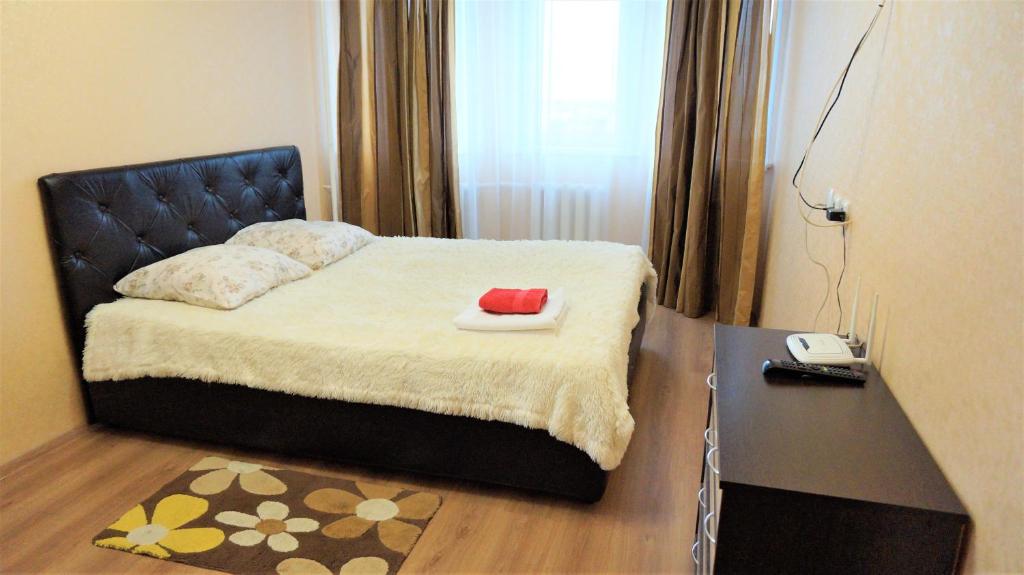 a bedroom with a bed with a red hat on it at Apartment Over The City in Vladimir