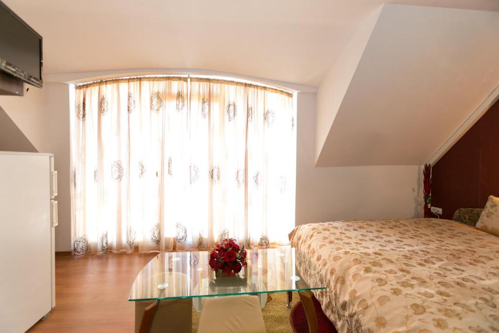 a bedroom with a bed and a glass table in front of a window at Guest Rooms Tivona in Pazardzhik