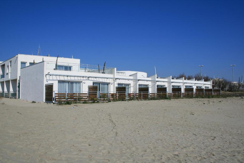 un edificio bianco sulla spiaggia vicino alla sabbia di Résidence Coté Mer a La Grande-Motte