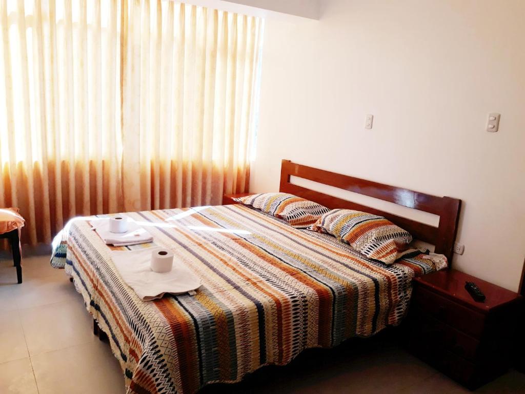 Un dormitorio con una cama con una mesa con dos tazas. en Alojamiento Huaraz, en Huaraz