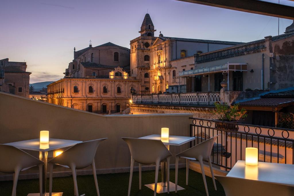 un patio en la azotea con mesas y sillas en un balcón en Hotel Porta Reale, en Noto