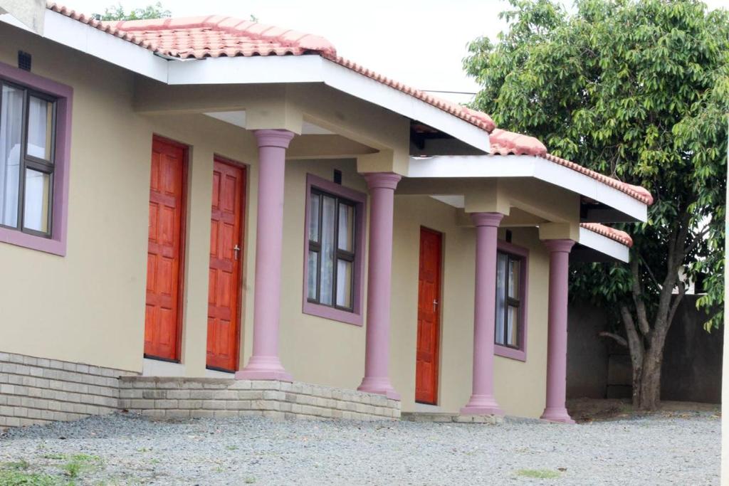 Una pequeña casa con puertas rojas. en Mbopha Guest House, en Ulundi