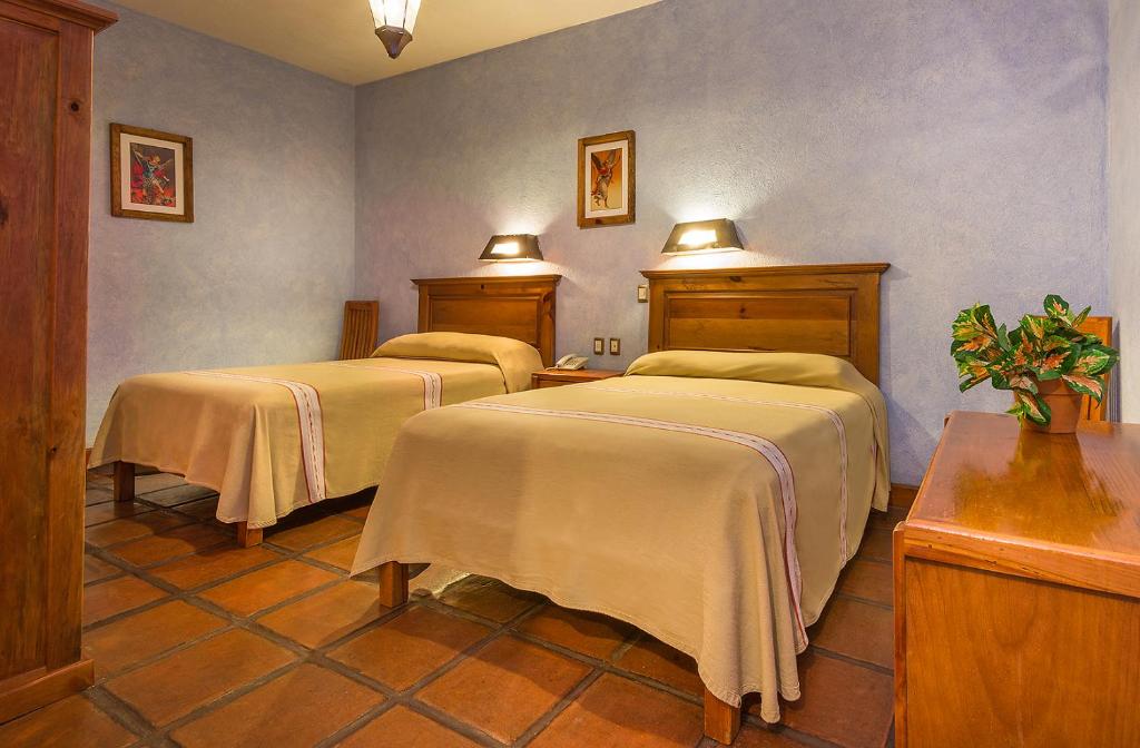 Habitación con 2 camas y mantas. en Hotel Refugio del Angel, en Pátzcuaro