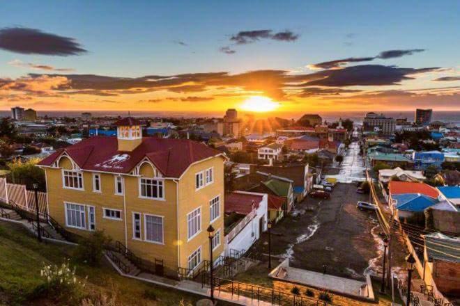 einen Sonnenuntergang über einer Stadt mit einem gelben Haus in der Unterkunft Hotel Boutique La Yegua Loca in Punta Arenas