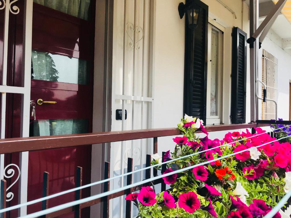 einen Balkon mit rosa Blumen und einer roten Tür in der Unterkunft Gemma Apartments Milano Rho Fiera Apt2 in Lainate