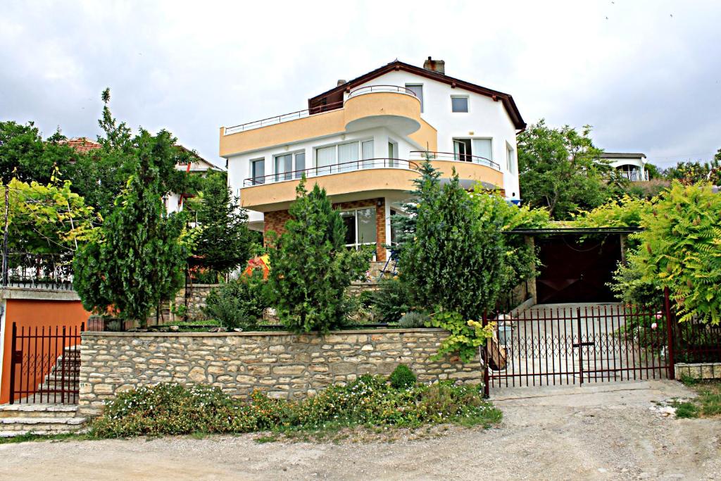 a house with a stone wall and a fence at Popov Guest House in Balchik