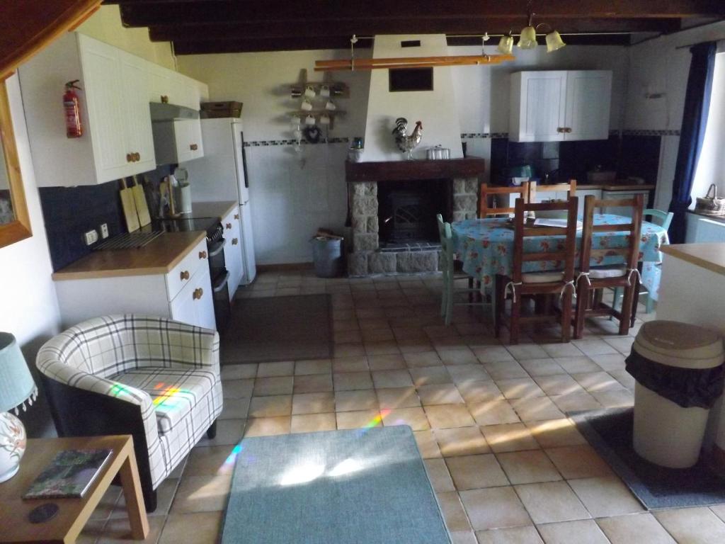 a kitchen and living room with a table and a fireplace at Les Chouettes in Callac