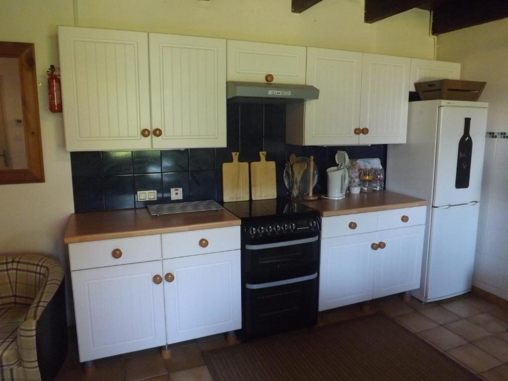a kitchen with white cabinets and a black stove at Les Chouettes in Callac