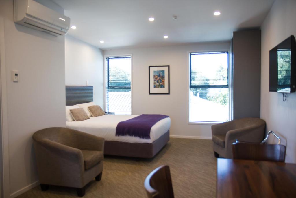 a hotel room with a bed and two chairs at 850 Cameron Motel in Tauranga