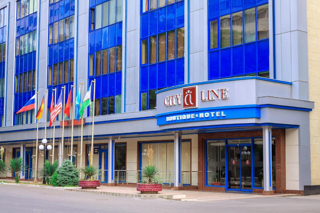 City Line Boutique Hotel في طشقند: مبنى على خط المدينة مع أعلام أمامه