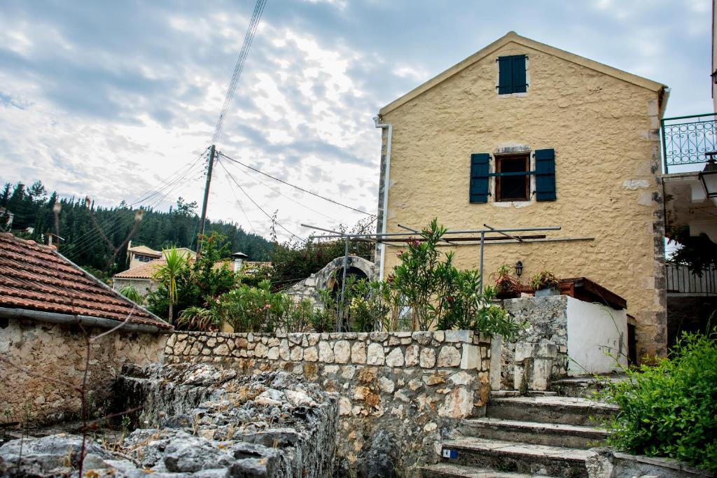 a house with stairs in front of a stone wall at Nostos Residence - Apartment Terra in Tselendáta