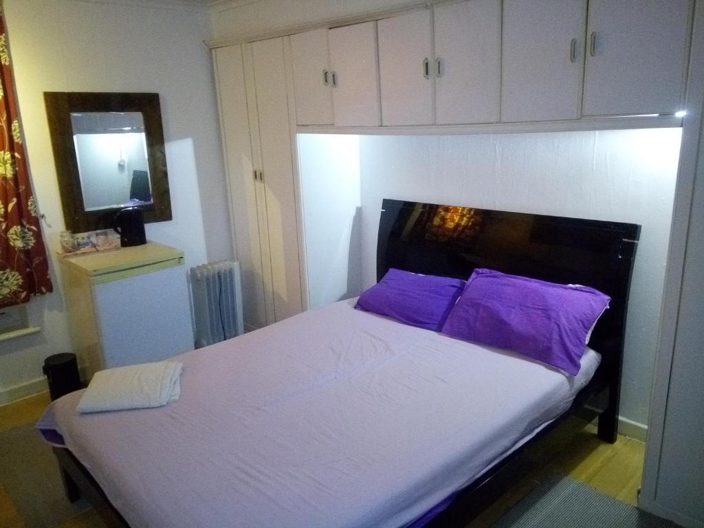 a bedroom with a bed with purple pillows and a mirror at Private Cosy Roomz in London