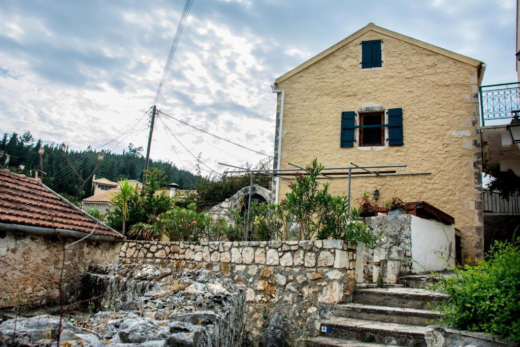 a house with stairs in front of a stone wall at Nostos Residence - Apartment Mare in Matsoukáta