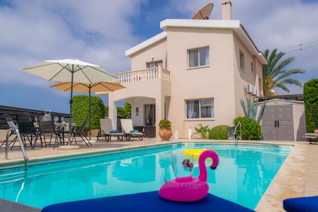 una piscina con un cisne rosa frente a una casa en Villa Puccini: Luxury villa with private pool, en Peyia