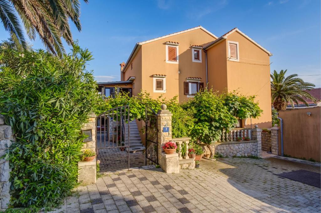 una casa con un cancello e alberi di fronte di Apartments Beba a Mali Lošinj (Lussinpiccolo)