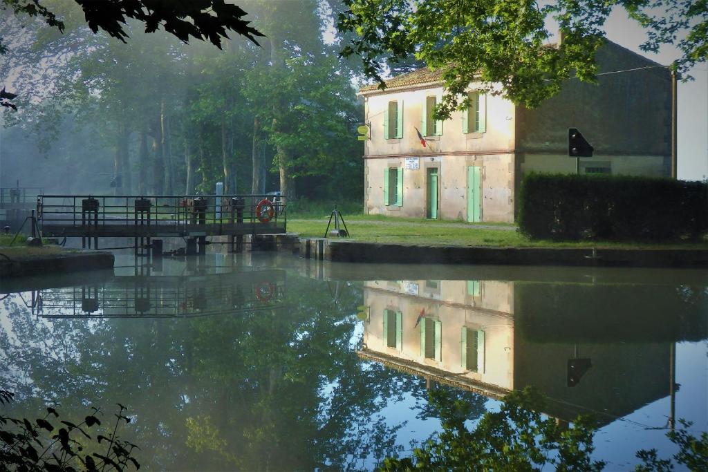 een reflectie van een gebouw in een waterlichaam bij gîte de la Domergue in Mas-Saintes-Puelles