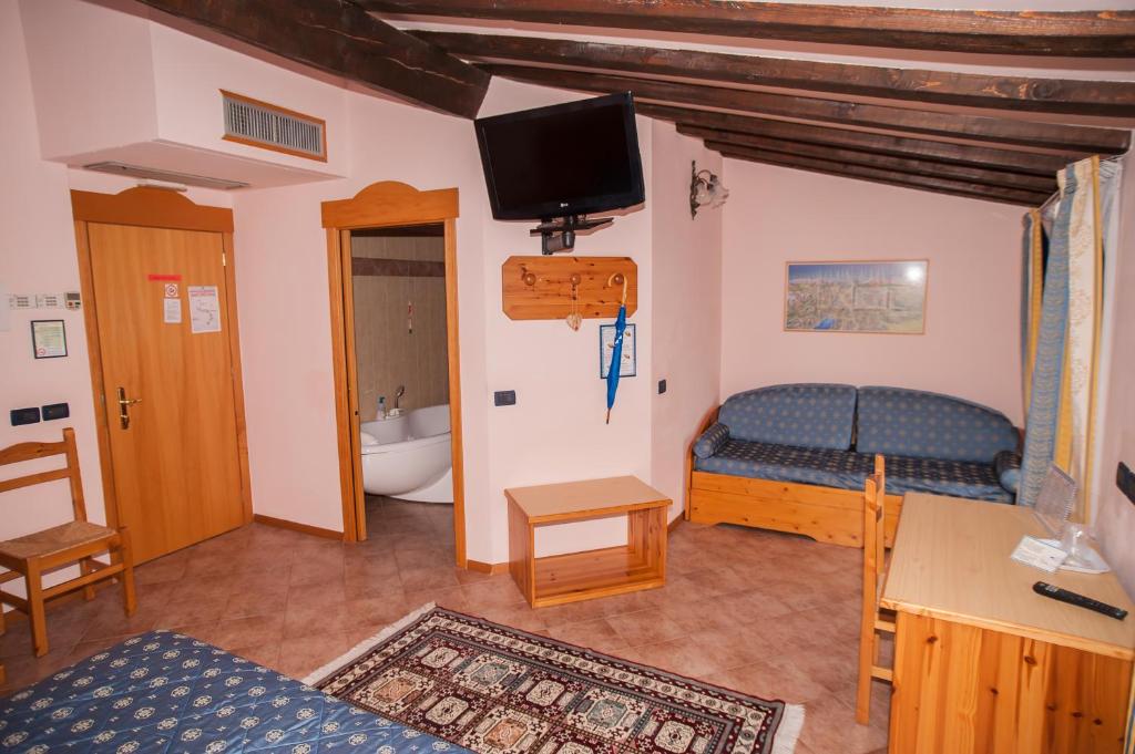 a bedroom with a bed and a tv on the wall at Hotel Vittoria in Riva del Garda