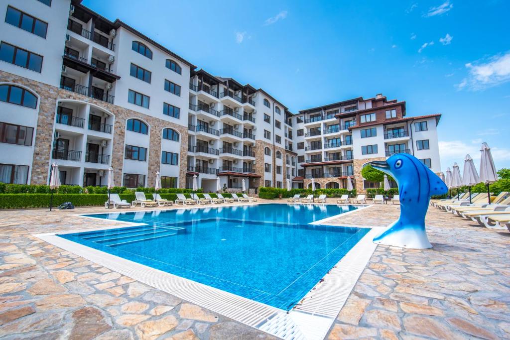 une piscine avec une statue de dauphins à côté d'un bâtiment dans l'établissement Apollon Apartments, à Nessebar