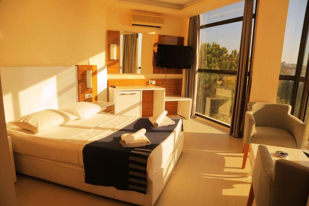 a bedroom with a bed and a large window at WA Çeşme Farm Hotel Beach Resort & Spa in Çeşme