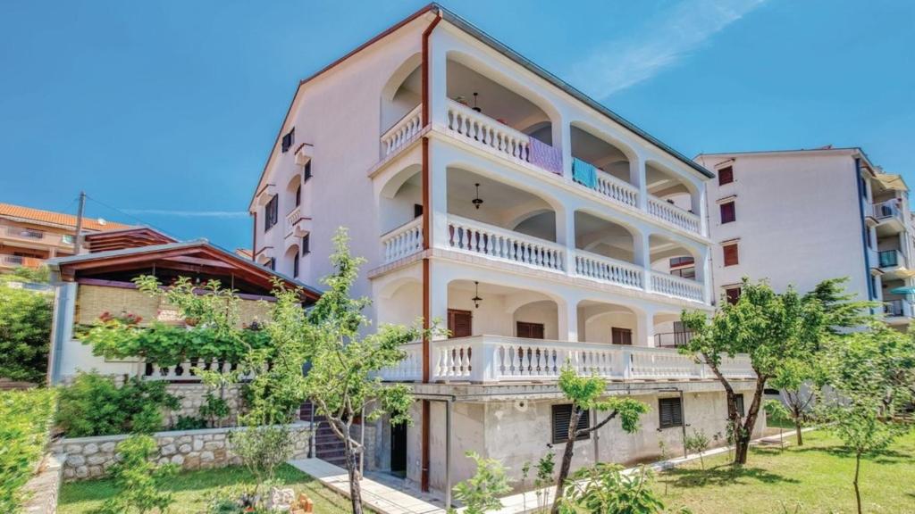 an apartment building with white balconies and trees at Apartments SKULIN in Novi Vinodolski