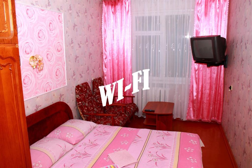 - une chambre rose avec un lit et une télévision rideaux dans l'établissement Prime Home 4, à Tchernihiv