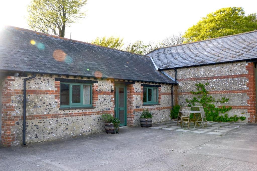 una casa de ladrillo con una mesa y una silla delante de ella en Top Parts Bed & Breakfast, en Abbotsbury