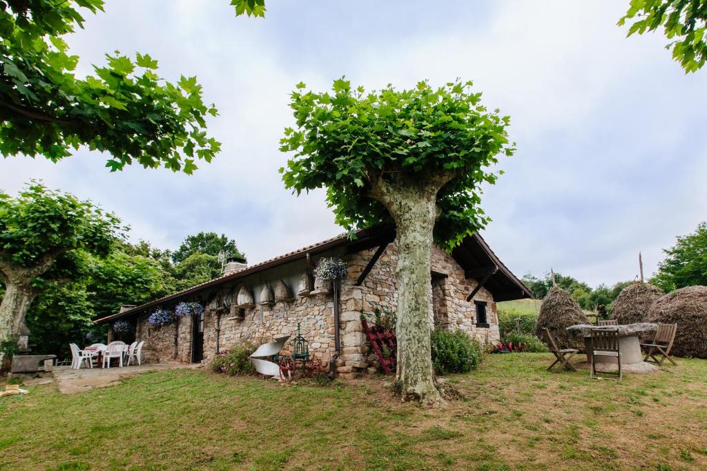 a stone house with a tree in front of it at Gite Manttu in Urrugne
