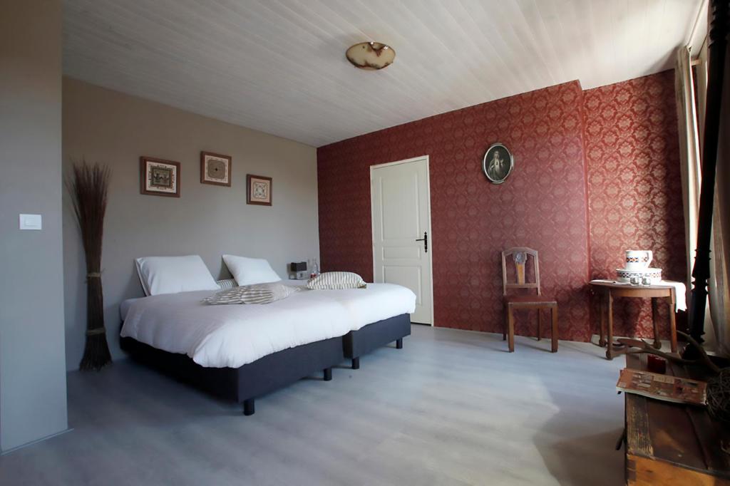 a bedroom with two beds and a red wall at Arara in Montfaucon-dʼArgonne