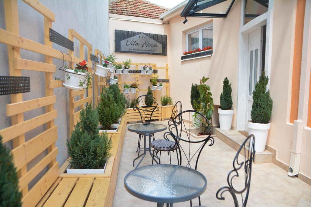 a patio with tables and chairs and potted plants at Vila Nova in Niš