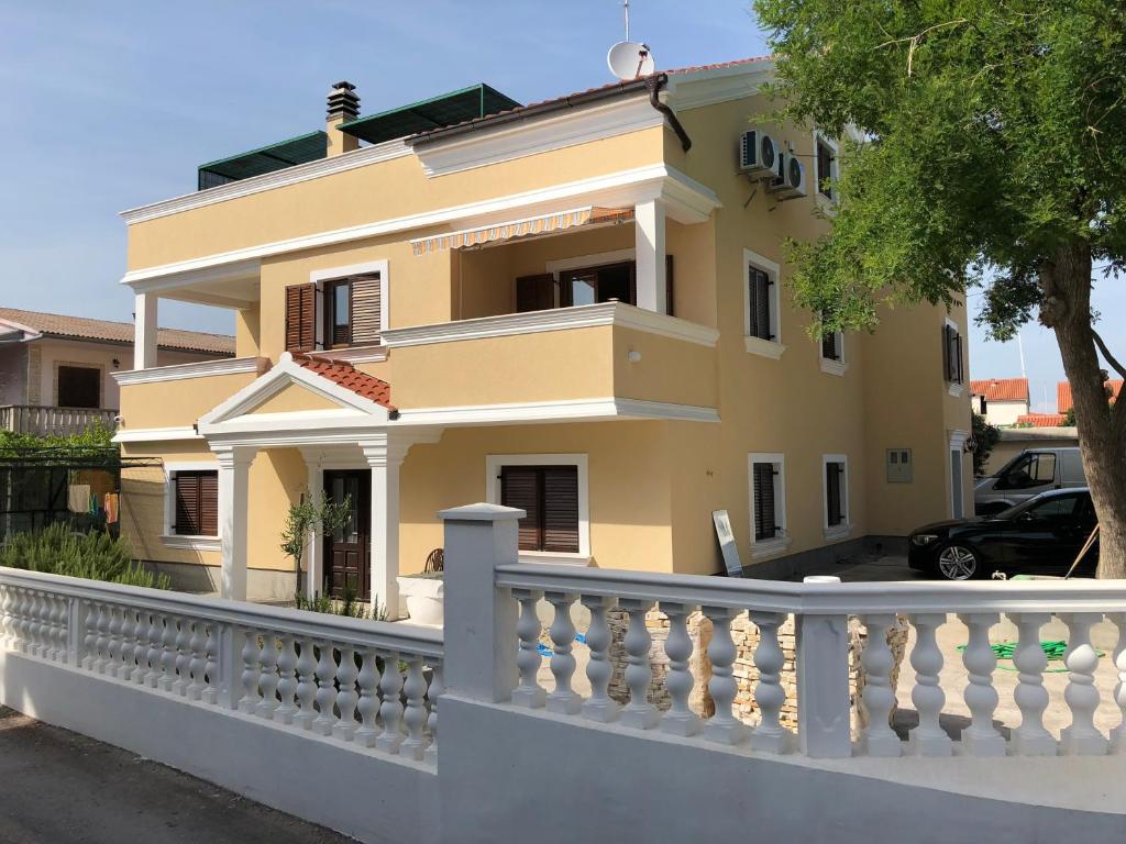 a yellow house with a white fence at Villa Sophie in Betina