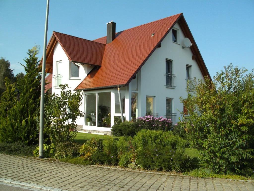 een wit huis met een oranje dak op een straat bij Ferienwohnung Belisa in Burgau