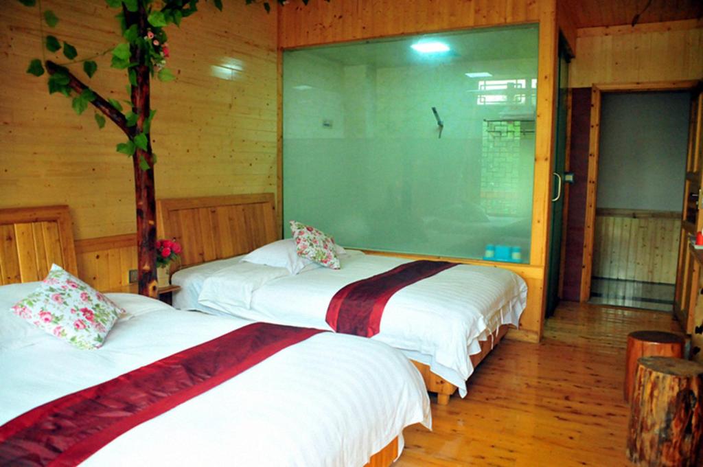 two beds in a room with wooden walls at Yangjiajie Inn in Zhangjiajie