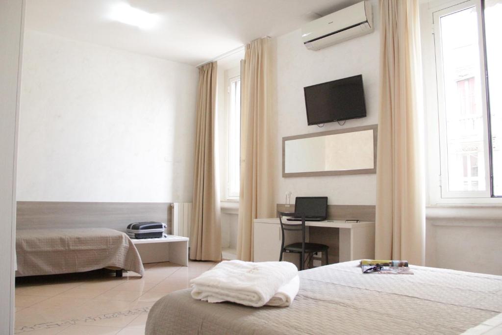 a hotel room with two beds and a television on the wall at Hotel Siro in Milan