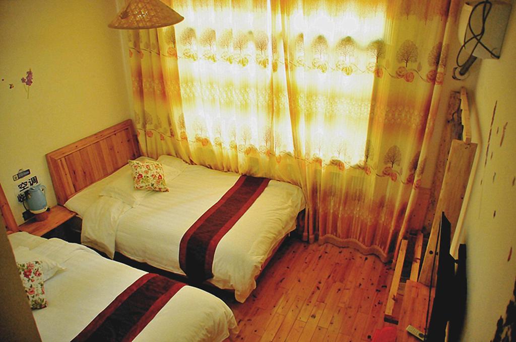 a bedroom with two beds and a window at Yangjiajie Inn in Zhangjiajie
